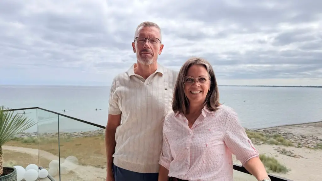 Tom og Vinni på altanen med stranden i baggrunden